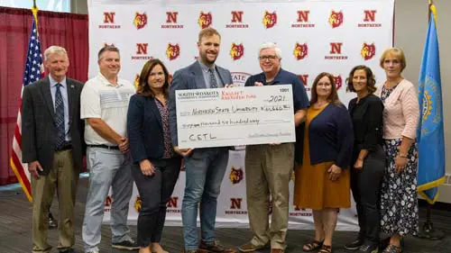 A group presenting a check in front of an NSU backdrop